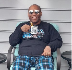 A man sits in a chair while holding a cup of coffee.