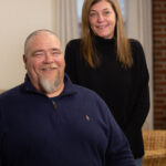 A man and woman pose for a photo in their home.