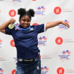 A child poses for a photo with a gold medal. 