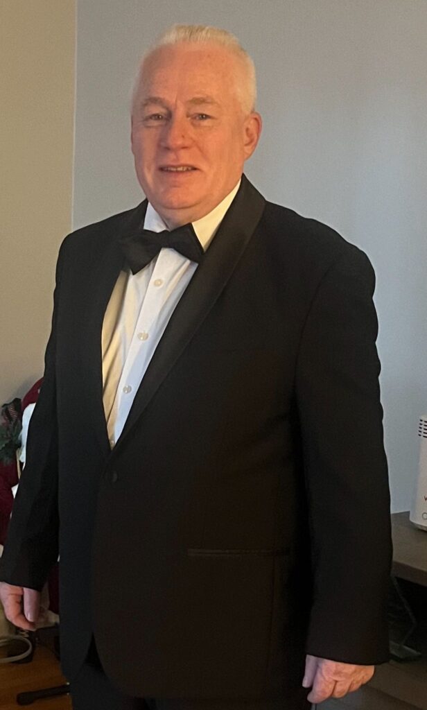 A man in a tuxedo poses for a photo. 