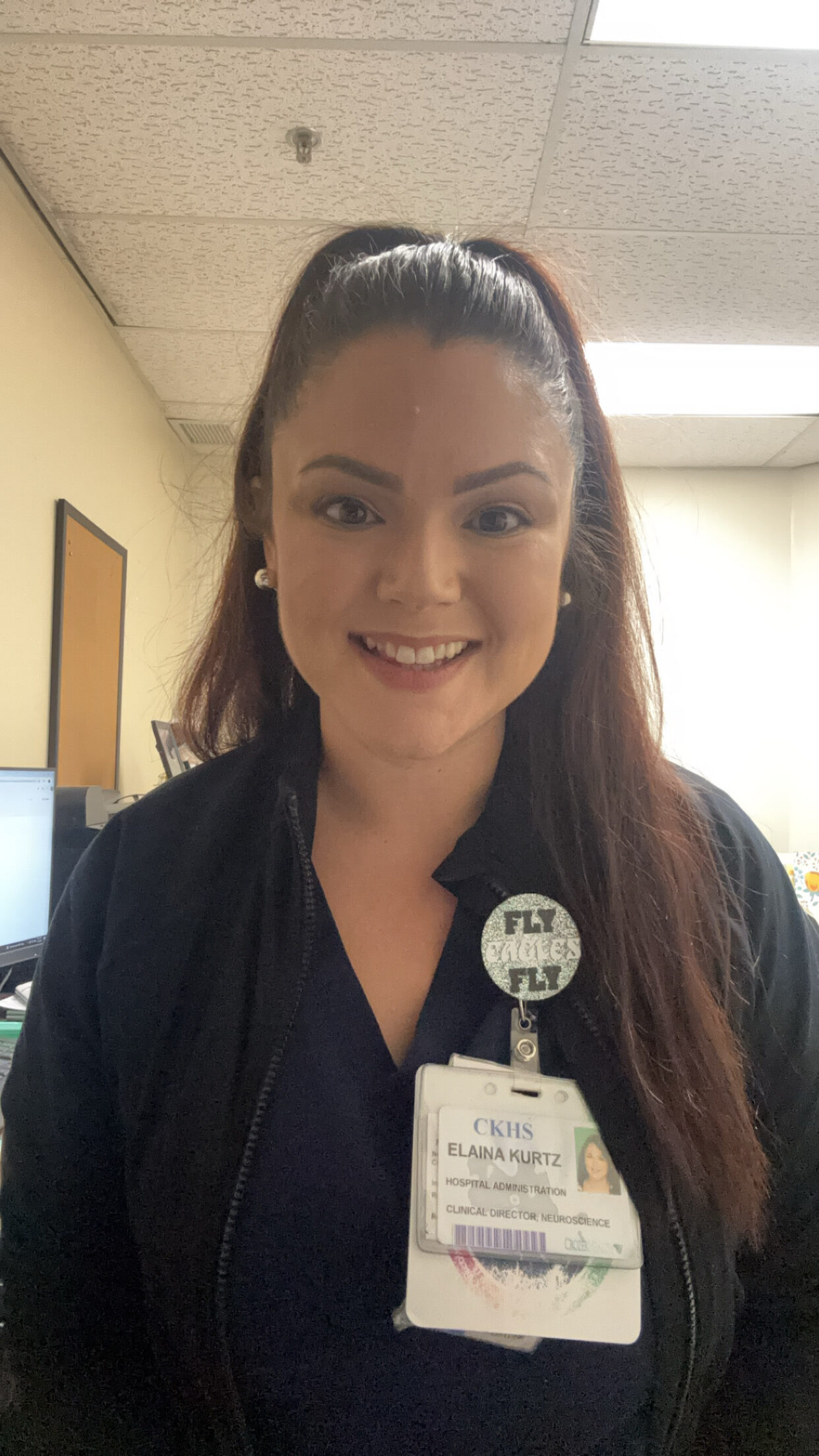 A woman poses for a photo in a hospital hallway.