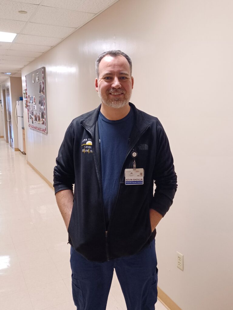 A man poses for a picture in a hospital hallway.