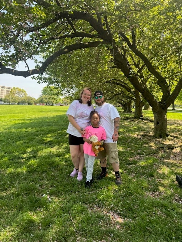 A young girl and two young adults pose for a picture.