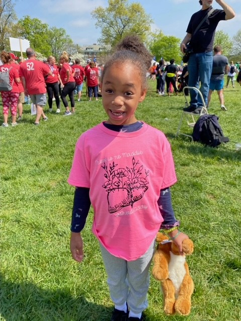 A young girl poses for a photo in her pink t-shirt.